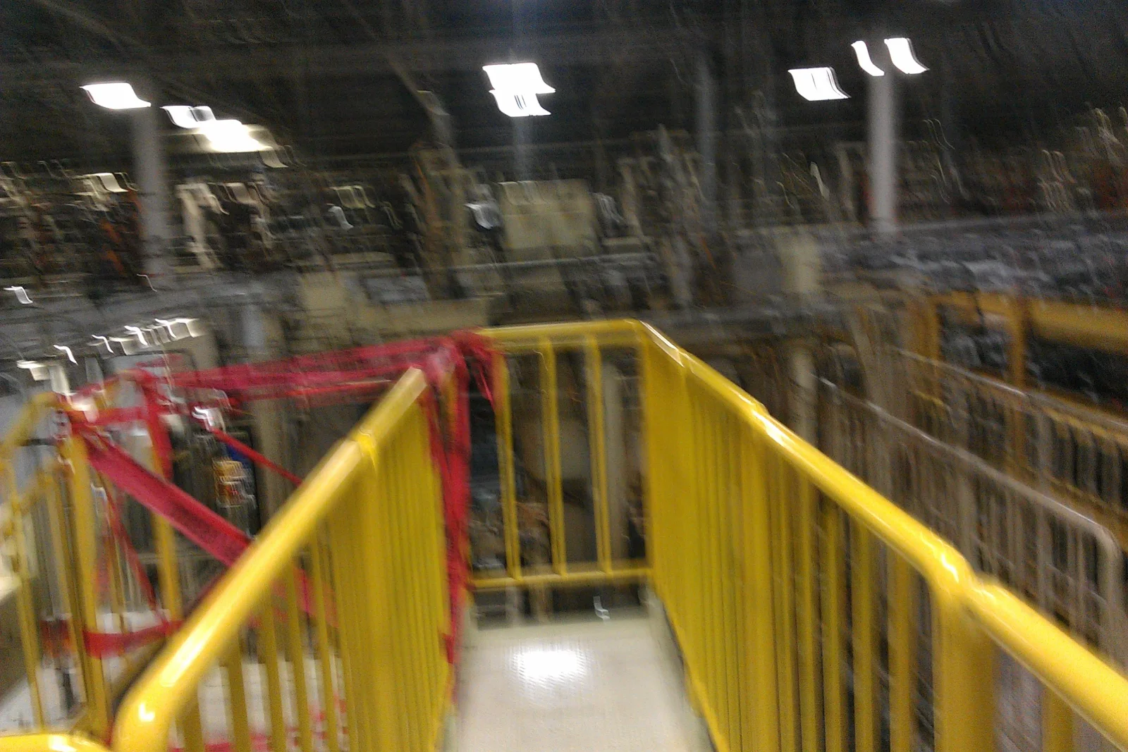 Yellow steel safety railings along an elevated walkway with red strapping inside an industrial storage facility