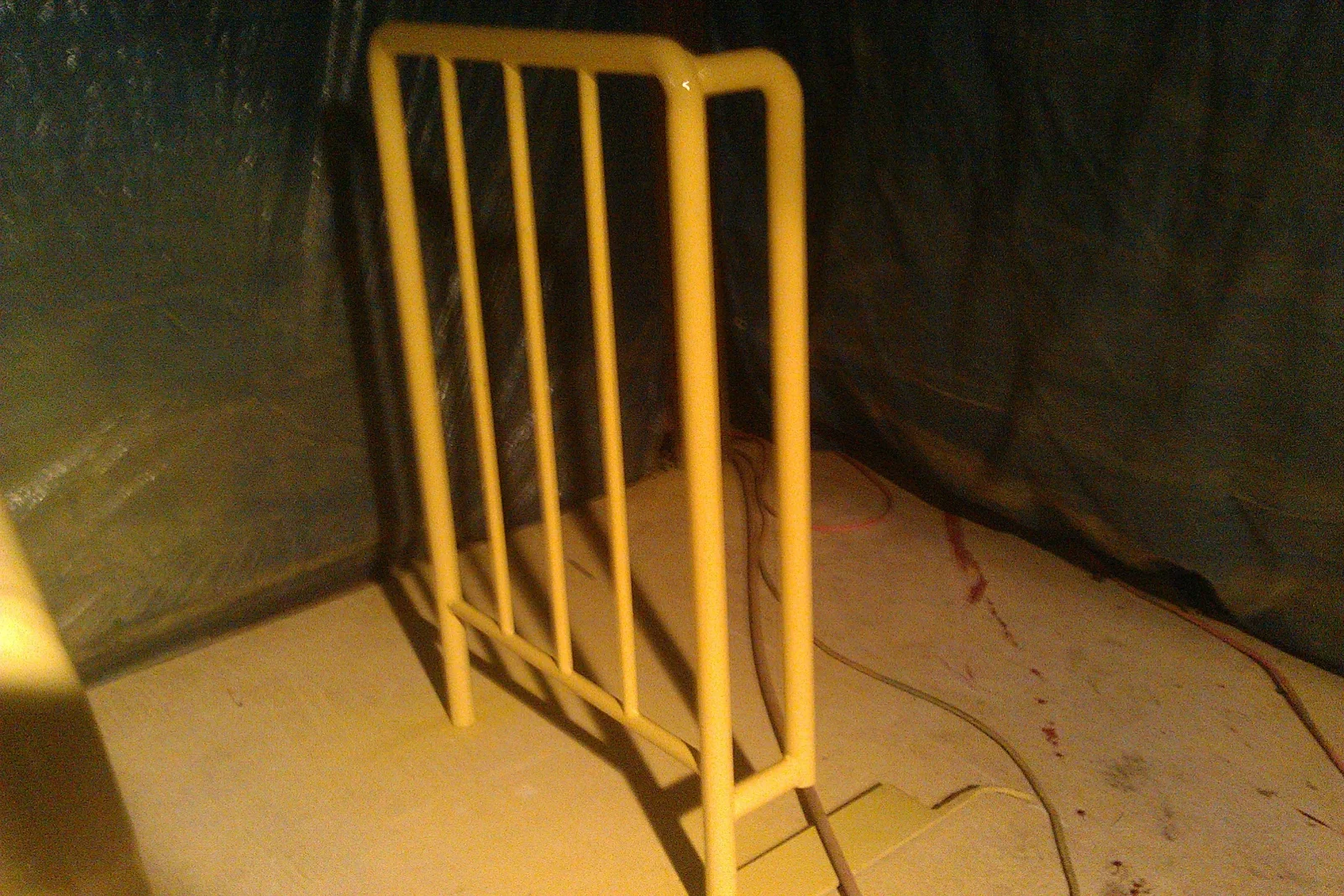 Cream painted tubular steel panel with five vertical bars and horizontal base rail on concrete floor